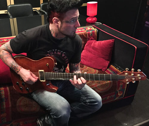 Man playing guitar on a couch.